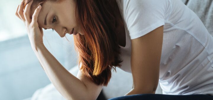 Caregiver sitting on side of bed grieving