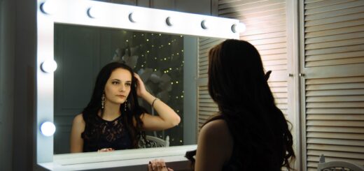 Dark haired younger woman looking in a mirror feeling. Reflection shows distress over passing time.