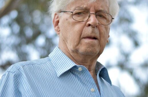 Older man with white hair in an outdoor setting looking angry