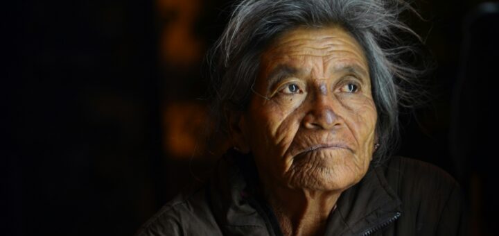 Darker skinned older woman with gray hair and vacant look in eyes
