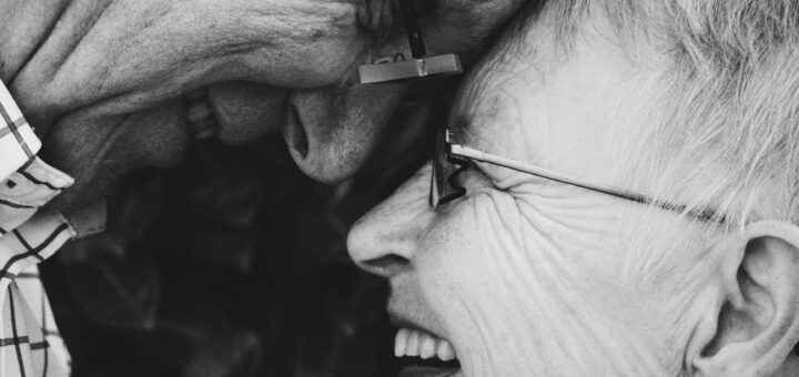 Black and white image of older man and woman forehead to forehead both of them smiling