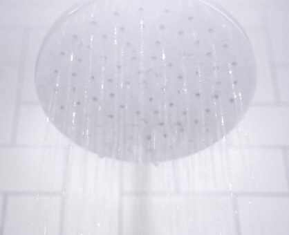 A white picture showing a shower head from below with water coming down