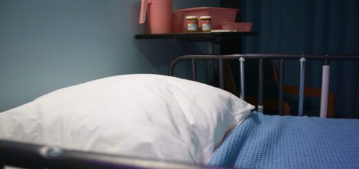 this indoor image shows a close up view of a white pillow and slue blanket framed by a wooden bed.
