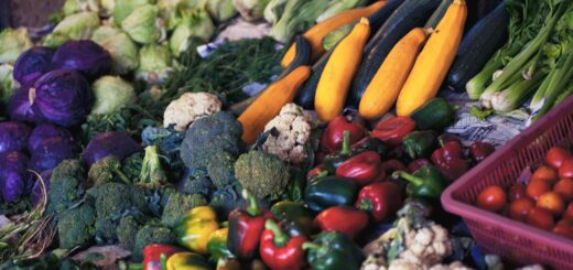 We see a colorful display of produce such as carrots, red and yellow peppers, broccoli, and mushrooms.