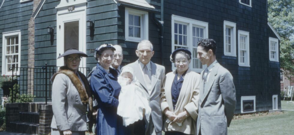 A vintage, faded color photo shows a group of older adults standing together, enjoying having their picture taken.
