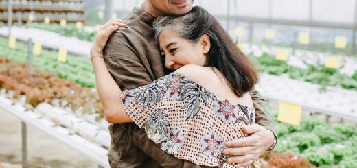 A healthy aging couple embraces in a garden center as they shop.